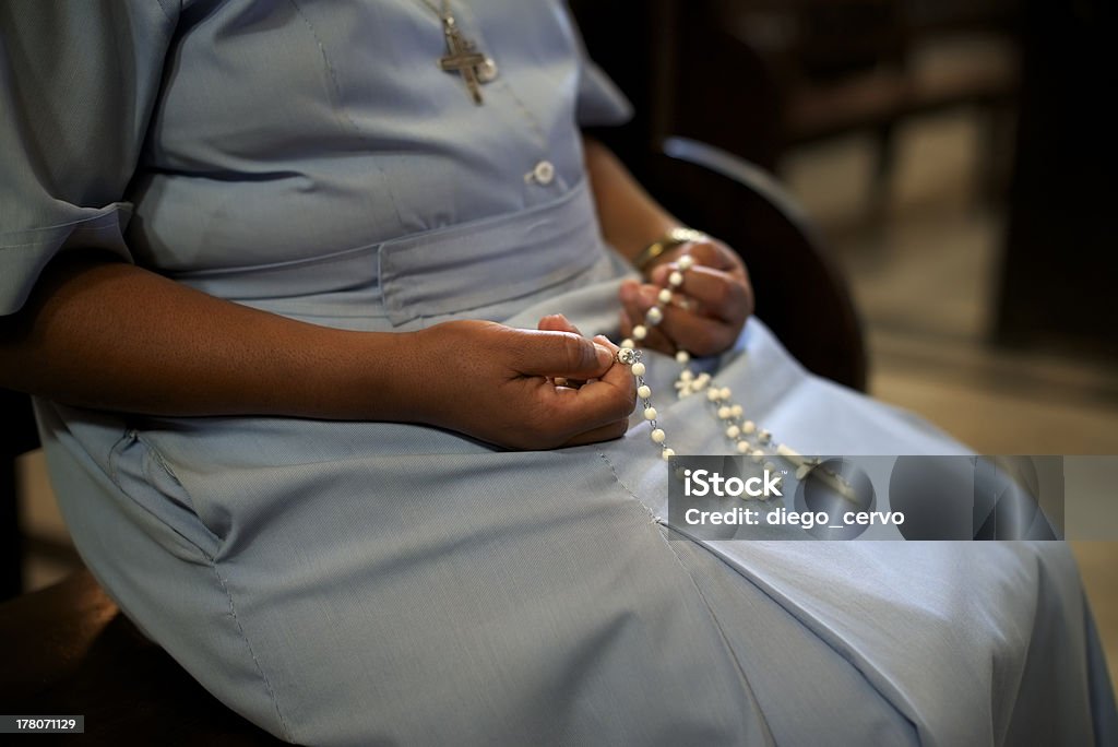 A Catholic woman holding beads in church People and religion, catholic sister praying in church and holding cross in hands. With model release Catholicism Stock Photo
