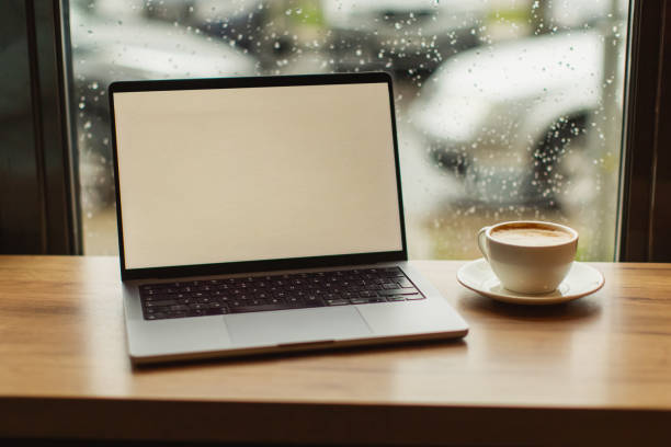 istock Laptop and cup of coffee on table by the window. 1780714127
