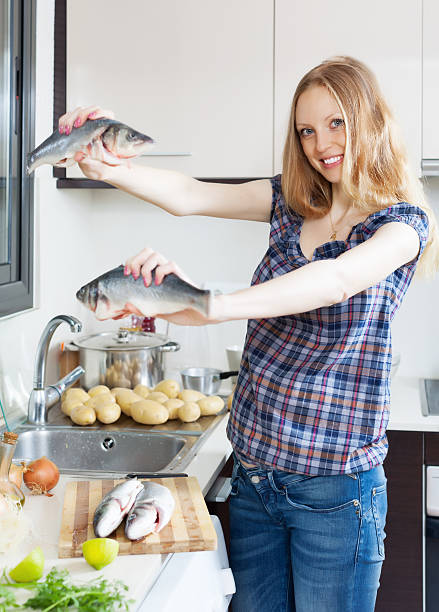 istock Smiling blonde woman with seabass fish 178071706