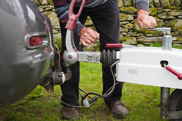 Close-up of a man hooking up a trailer to a car Man hooking up caravan to car tow bar. hitchhiking stock pictures, royalty-free photos & images