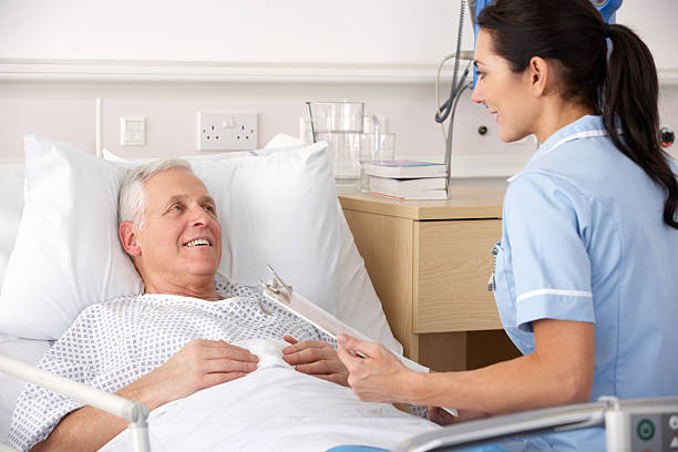 Nurse with male patient in UK Accident and Emergency Nurse and male patient in UK Accident and Emergency looking at each other having a discussion night table stock pictures, royalty-free photos & images