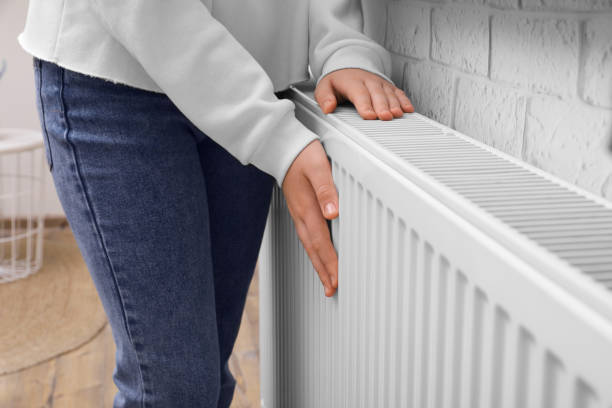 istock Girl warming hands on heating radiator indoors, closeup 1780752711