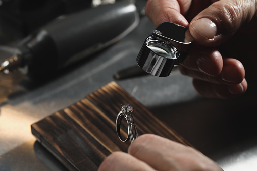 Professional jeweler working with ring at table, closeup
