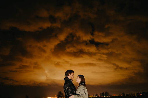 couple in love at night under a red cloudy sky in a field. Mystical concept of apocalypse.