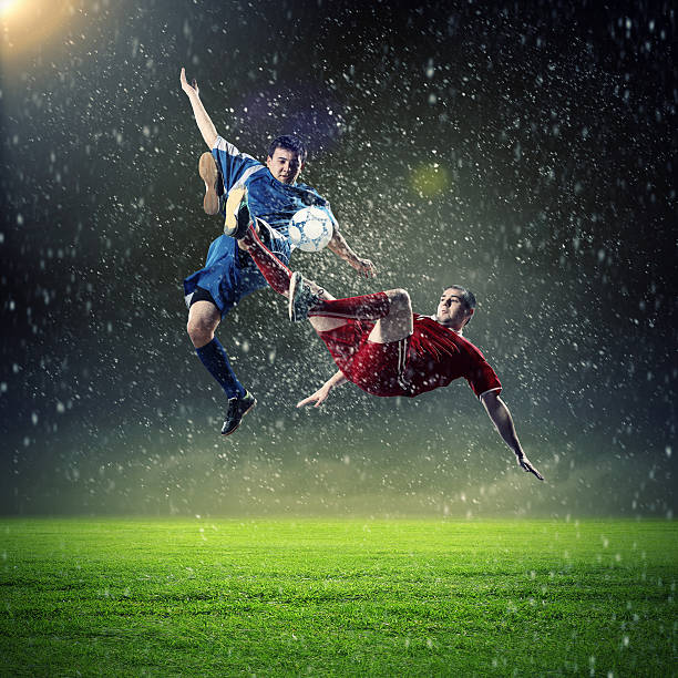 two football players striking the ball stock photo