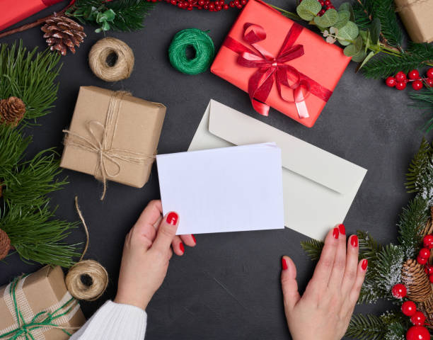 istock White envelope and Christmas wreath on a black background, top view 1780764318