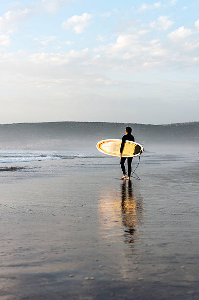 istock Surfer carrying his board on a misty shore 178077496