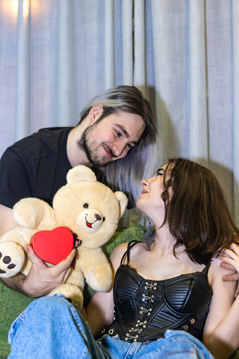 happy man giving a gift to his partner. A man holding a teddy bear next to a woman