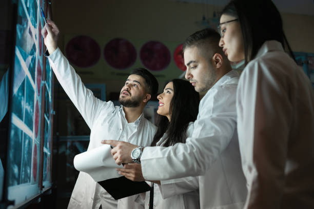 A group of surgeon interns is studying fetal development at different stages of pregnancy. Health education concept. Medical students in the classroom with images of ultrasound