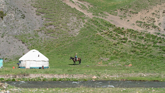 Kyrgzystan - May 2022: Kids near a traditional Yurt tent in Kyrgyzstan countryside. Yurt tents are traditional, portable tents made of felt that are used as a form of accommodation in the country.