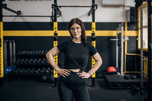One woman, portrait of a fit young woman standing alone in gym.
