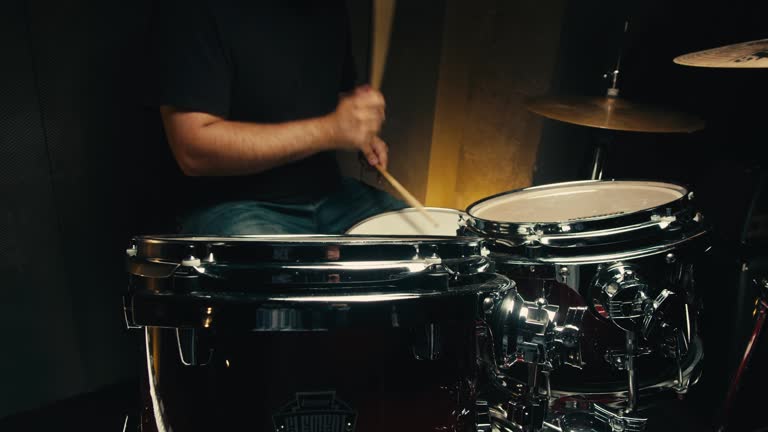 Expressive drummer young man professionally playing on dums in studio room close-up. Rock metall music artist