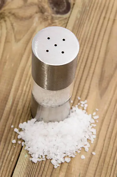 Saltshaker with Salt on wooden background