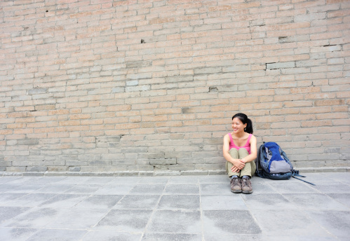woman sit against ancient small wild goose pagoda wall,xian,china 