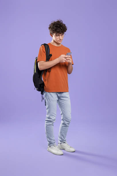 istock Cute teenage boy using smartphone on violet background 1780824457