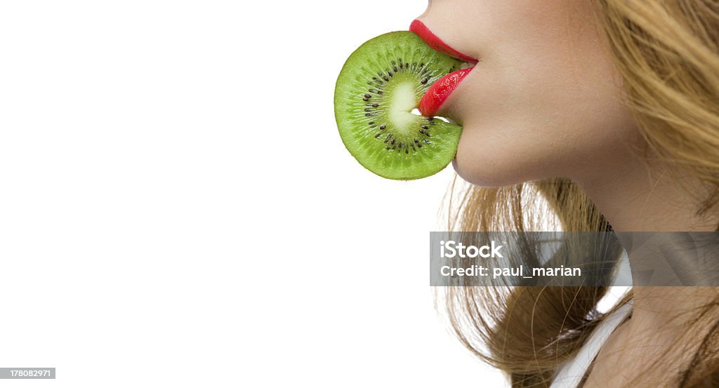 Gril's red lips biting a slice of kiwy with copyspace Lips with red lipstick biting a slice of kiwi on white background 20-29 Years Stock Photo