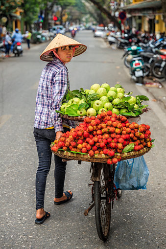 Vietnamese woman selling tropical fruits, old town in Hanoi, Vietnam. Hanoi is the capital of Vietnam, is located in the central area of the Red River Delta, and Hanoi is the second largest city in Vietnam.