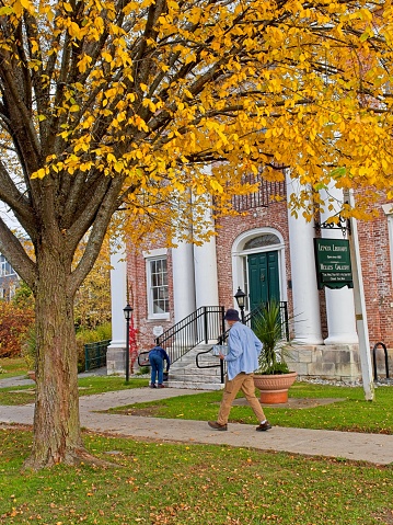 Lenox, Massachusetts - USA, October 26, 2023. Readers walk to the Lenox public library and Welles Gallery on Main street in Lenox Massachusetts. Lenox a quaint charming community in the Berkshire mountains of western Massachusetts.