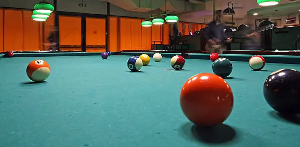 smoky poolroom with marbles on the carpet and attentive players