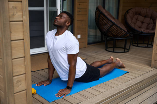 istock Man practices yoga on a wooden terrace 1780889456