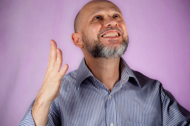 Man making sign with his hand against pink background.
