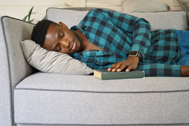istock Curly-haired man dozed off with a book on the sofa 1780901502