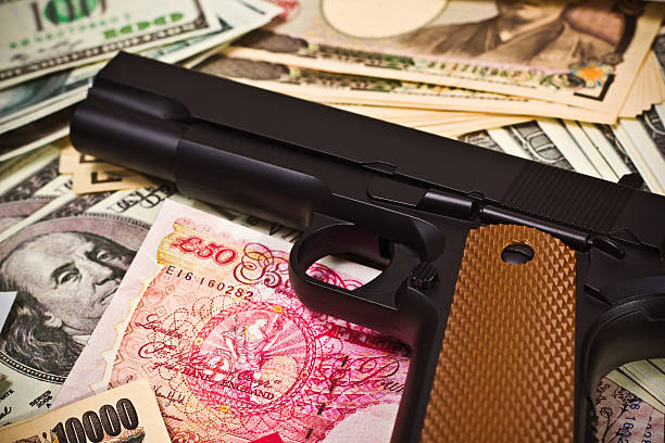 International Crime A gun placed on iternational currencies portrays linkage of international crime wrongdoer stock pictures, royalty-free photos & images