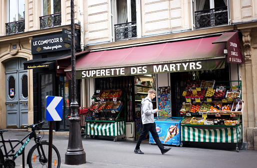 Paris, France: A young man walks past a green grocer while looking at his phone on Rue des Martyrs in the 9th arrondissement.