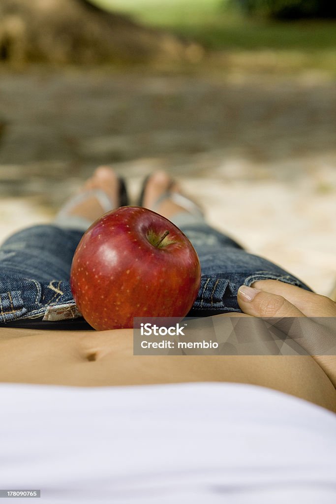 Red apple on the belly Red apple on the middle of the belly of a slim girl. Abdomen Stock Photo
