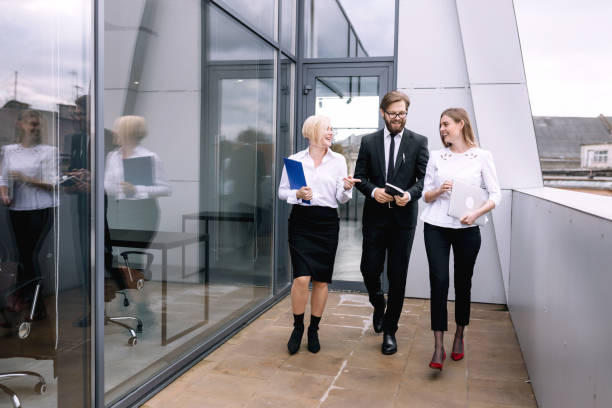 istock Three happy business people are walking outdoors together with a laptop and documents for a project presentation. 1780917815