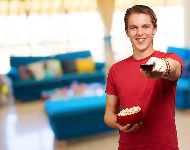 portrait of a young man holding popcorn, indoor