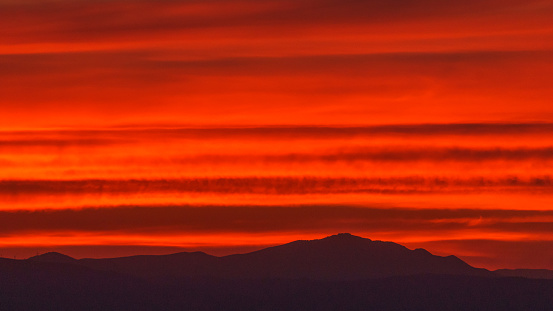 Orange warm colorful sky from sunset over silhouette of mountain landscape