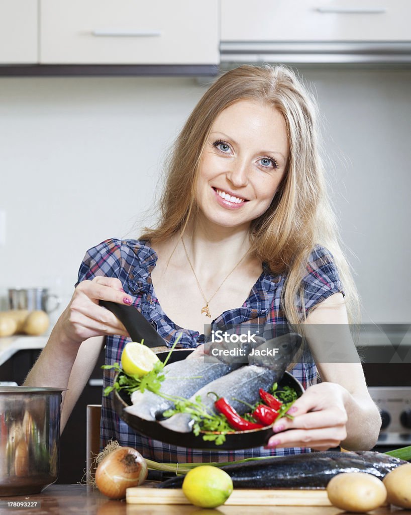 Lächelnde blonde Frau Kochen lubina im frying pan - Lizenzfrei Eine Frau allein Stock-Foto