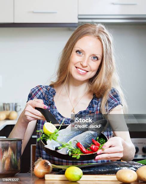 Lächelnde Blonde Frau Kochen Lubina Im Frying Pan Stockfoto und mehr Bilder von Eine Frau allein - Eine Frau allein, Fisch, Frauen