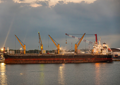 Guatemala, Puerto Quetzal - July 20, 2023: Evening sky and lights. Large bulk carrier Clipperfair closeup docked and cranes working on it
