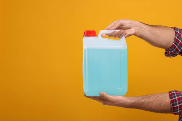 istock Man holding canister with blue liquid on orange background, closeup. Space for text 1780939277