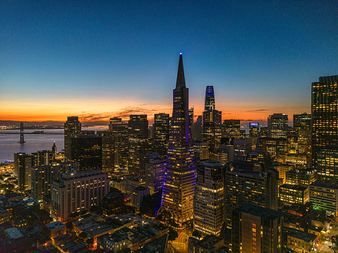Aerial view of the San Francisco skyline illuminated with lights in the early morning sunrise. Looking out over iconic buildings.