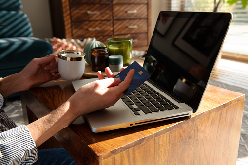 Manicured hands of young woman making purchases in online store and paying with credit card