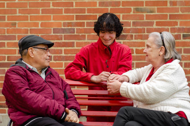 grandparents with teen boy grandson sitting on a bench outdoors grandparents with teen boy grandson sitting on a bench outdoors grandmother real people front view head and shoulders stock pictures, royalty-free photos & images