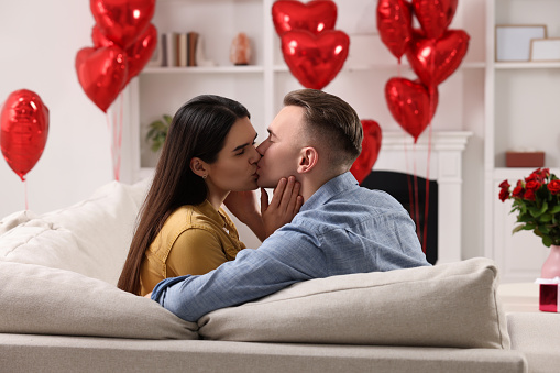 Lovely couple kissing on sofa at home. Valentine's day celebration