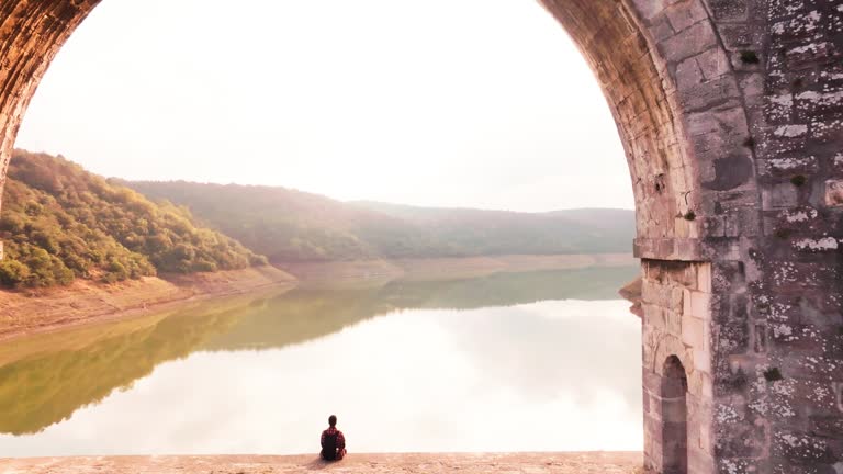 tourist sitting on the arch of the historical bridge watching the view