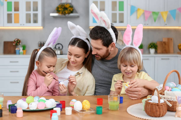 istock Happy family painting Easter eggs at table in kitchen 1780964631