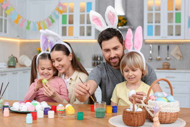 istock Happy family painting Easter eggs at table in kitchen 1780964666