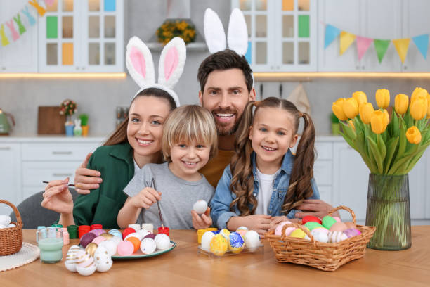キッチンのテーブルでイースターエッグを持つ幸せな家族の肖像画 - bunny painting ストックフォトと画像