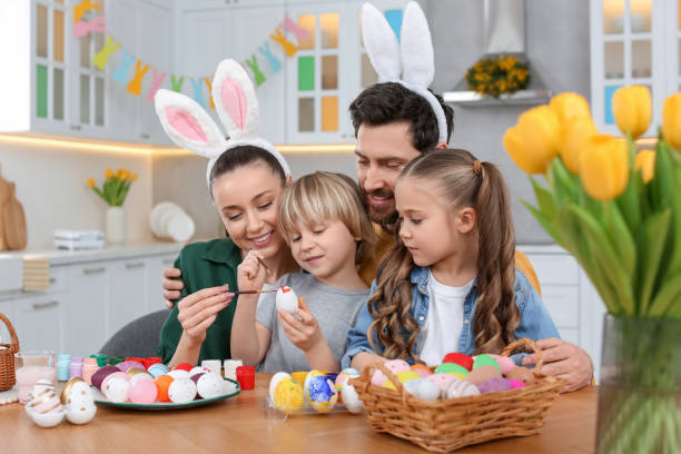istock Happy family painting Easter eggs at table in kitchen 1780965043