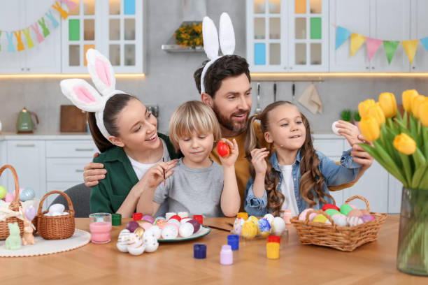 istock Happy family painting Easter eggs at table in kitchen 1780965248