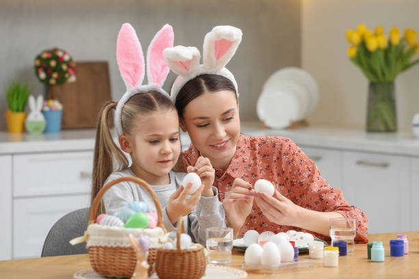 istock Mother and her cute daughter painting Easter eggs at table in kitchen 1780965304