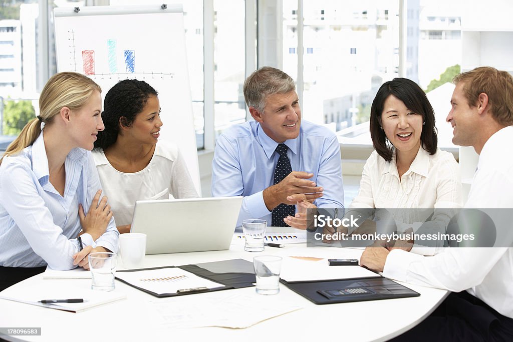 Business meeting in an office Business meeting in an office with colleagues sitting around table talking Corporate Business Stock Photo