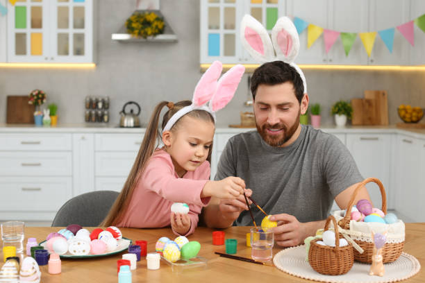 istock Father and his cute daughter painting Easter eggs at table in kitchen 1780966379