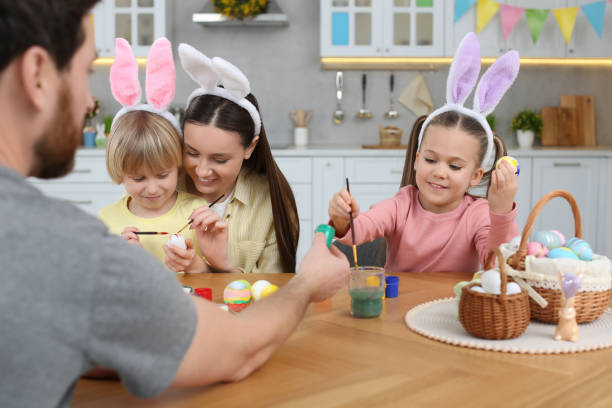istock Happy family painting Easter eggs at table in kitchen 1780966437